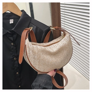 Close-up of contrast straw crescent bag featuring woven texture and brown leather strap