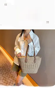 Detail of woven straw tote bag with brown leather handles and criss-cross weaving