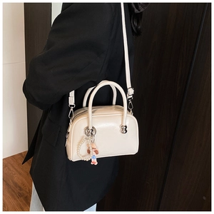 Detail of a beige leatherette bowling bag with pearl cartoon charm on a female model