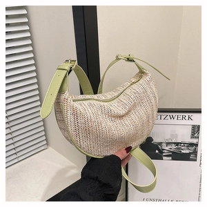 Close-up of beige herringbone straw weave and green leather strap on a crescent bag