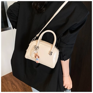Detail of a beige glossy bowling bag featuring a cute charm and silver-tone hardware