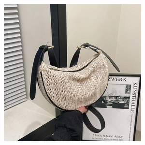 Detailed close-up of straw woven dumpling bag with black leather trim and golden hardware