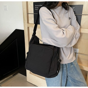 Detail of black nylon messenger bag with embossed text and adjustable wide strap