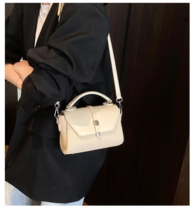 Detail view of cream leather and woven texture crossbody bag on a model in a black suit