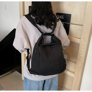 Side view of a large black nylon tote bag worn as a backpack for stylish travel use