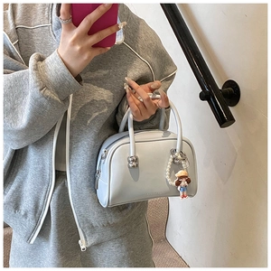 Detail of light blue Boston bag with matte leather finish and pearl charm accessory