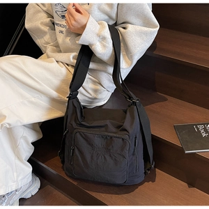 Detail shot of black nylon travel tote featuring multiple pockets and wide shoulder strap