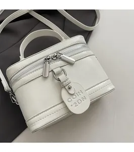 Detail shot of white vegan leather box bag with smooth double zippers and logo tag