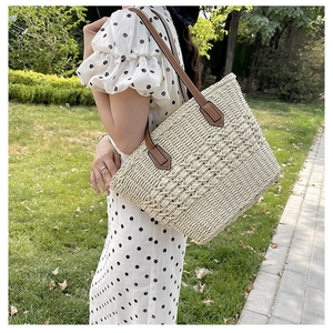 Detailed close-up of handmade woven straw tote texture with brown leather strap