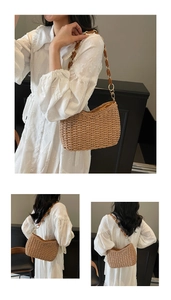 Detailed macro view of woven straw shoulder bag featuring an amber acrylic chain strap