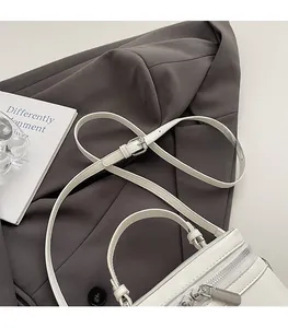 Detail of white box bag with adjustable leather strap and silver metal zipper closure