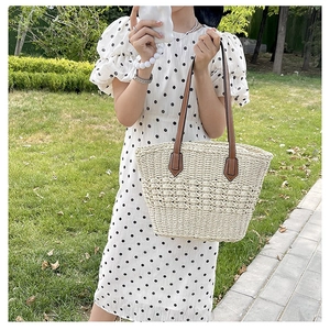 Detail of hand-woven straw tote with brown leather handles on a summer picnic background