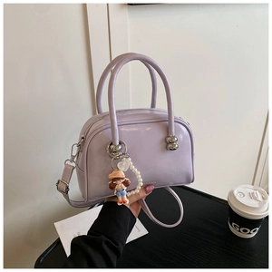 Detail of light purple glossy Boston bag with pearl doll charm and adjustable strap