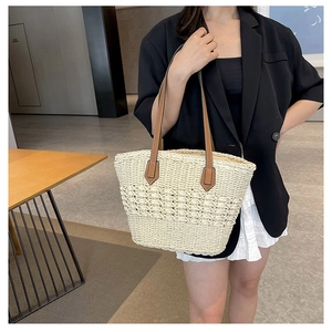 Detail of hand-woven straw tote bag with brown leather handles and hollow texture