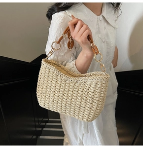 Detail of a beige straw handbag featuring a chic amber resin chain and metal ring accents