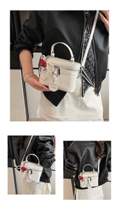 Detail of white box bag with pearl chain, heart charm and dual zipper closure