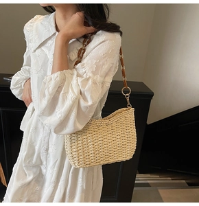 Detail of hand-woven straw shoulder bag with vintage resin chain and metal links