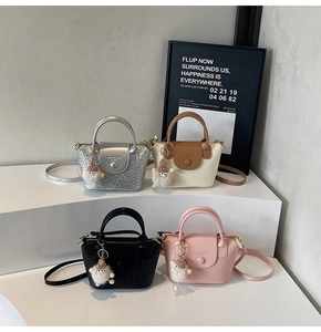 Détail de mini sacs seaux tressés avec breloques mouton en peluche et boucles métalliques