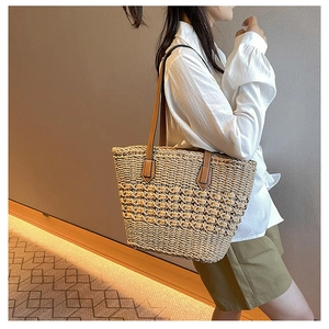 Detail of hand-woven straw tote bag with brown leather straps for resort fashion