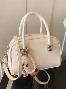 Creamy-colored minimalist leather bowling handbag with silver hardware and pearl charm
