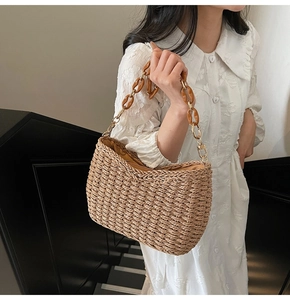 Detail of handwoven straw shoulder bag with amber resin chain link and summer texture