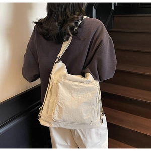 Close-up of beige nylon tote bag featuring white BIFW embroidery and adjustable shoulder strap