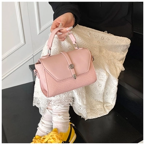 Close-up of pink leather crossbody bag featuring silver turn-lock and woven pattern detail