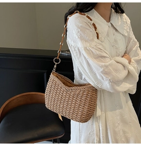 Detail of woven straw shoulder bag featuring chain strap and textured natural fibers