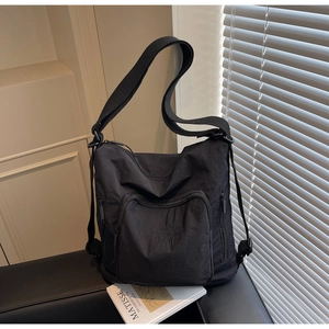Close-up of black nylon travel tote with zipper pocket on a stylish leather sofa