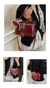 Detail view of red patent leather box bag with dual zippers and decorative pearl chain