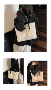 Close-up of cream woven tote bag featuring black leather trim and decorative tassel detail