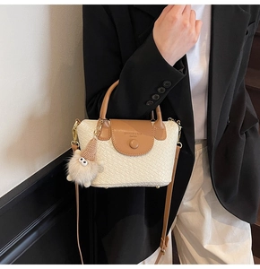Détail du sac seau à texture tressée avec rabat contrasté et breloque monstre en peluche