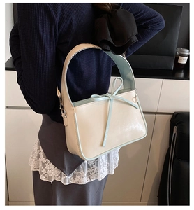 Détail du sac seau beige clair avec nœud bleu clair et boucle en métal poli
