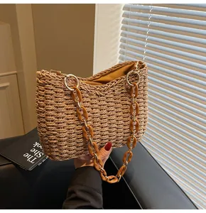 Detail of hand-woven straw bag with amber acrylic and gold metal chain strap and yellow lining