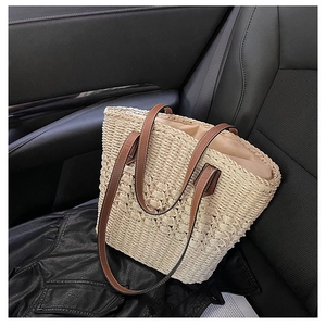 Close-up of the woven straw texture and premium brown leather handles of a beach tote bag