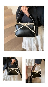Détail d'un sac à main bicolore en cuir verni avec un nœud blanc élégant en relief