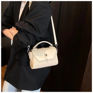 Chic beige crossbody bag with woven texture and metal buckle shown on a black suit blazer