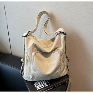 Detail of a beige nylon tote bag with artistic BIFW lettering on a black book
