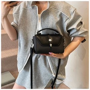 Close-up of black crossbody square bag with woven texture and silver metal clasp