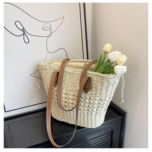 Detail of handwoven straw tote bag with brown leather straps and drawstring liner