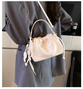 Detail of creamy white lychee grain leather cloud bag with drawstring and heart charm