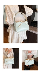 Détail du sac seau en cuir verni bleu menthe avec un nœud beige et une large bandoulière