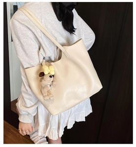 Detail of off-white tote bag with a cute puppy charm shown on a female model