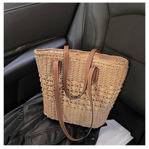 Detail of straw woven tote bag with brown leather handles on a leather seat