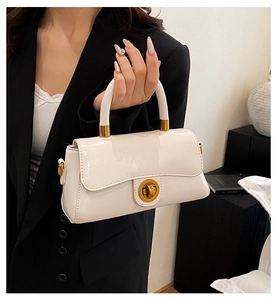 Détail du sac à main en cuir verni crème avec un fermoir pivotant doré élégant
