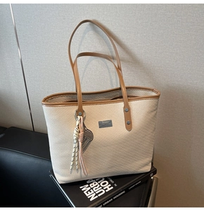 Close-up of beige tote bag fabric texture with leather strap and metal rivet details