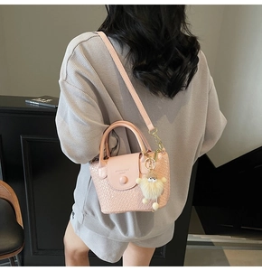Détail du sac bandoulière rose tressé avec un joli porte-clés en peluche d'agneau blanc