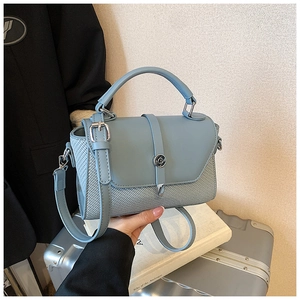 Detail view of the smog blue crossbody bag with woven texture and silver round metal lock