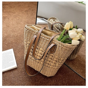 Detail of hand-woven straw tote with hollow pattern, leather straps and drawstring liner