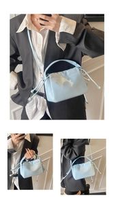 Detail of light blue bucket bag in litchi leather with drawstring and round handle